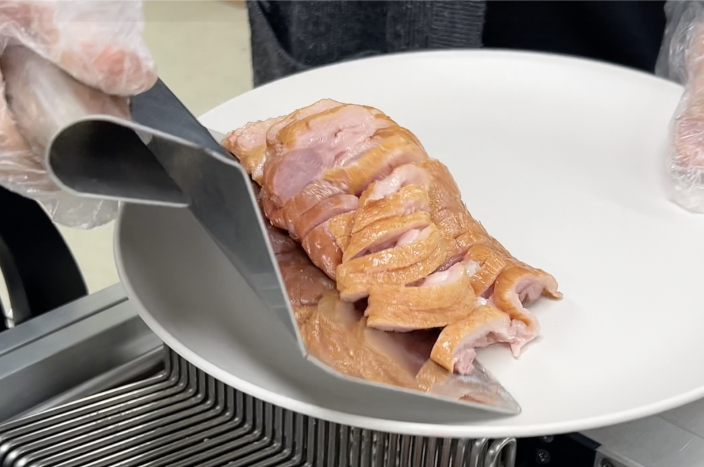 이지슬라이서로 세절 후 가지런히 정돈된 훈제오리를 접시에 담는 모습